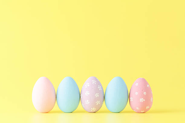 istock Easter eggs painted in pastel colors on yellow paper background 516789562