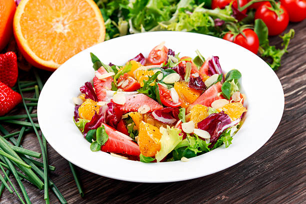 istock Fresh Orange, strawberry vegetables salad. on wooden table. 516790472