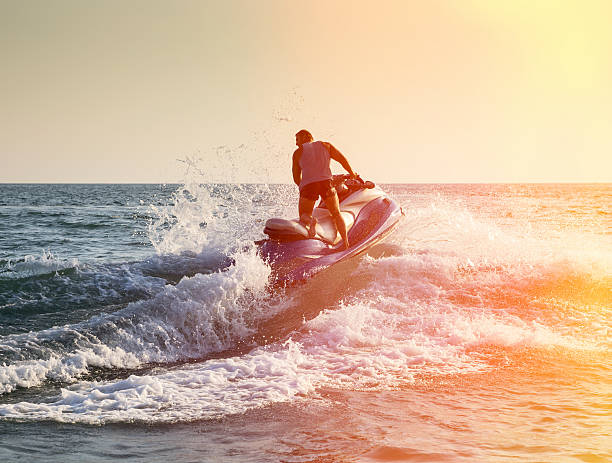 Silhouette of man on jetski at sea Silhouette of strong man jumps on the jetski above the water at sunset jet boat stock pictures, royalty-free photos & images