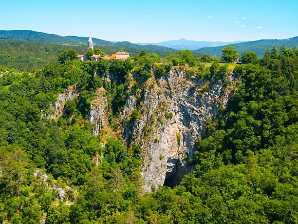 View of deep gorge of Reka River and village with rural church ,Skocjan Caves, Slovenia