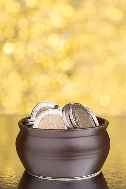 istock Brown pot with coins on golden background 516798608