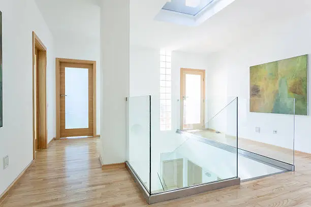 Stairs, glass banister and doors in modern hallway on the attic