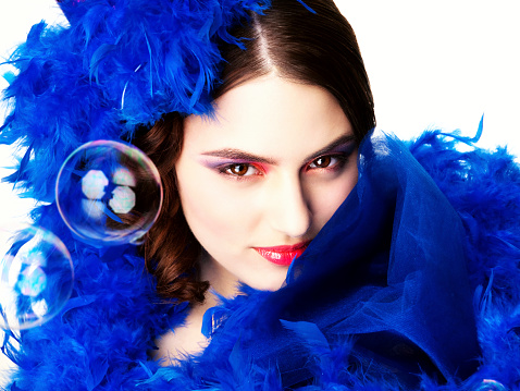 Portrait of the young beautiful woman with a  blue feather boa on a white background.