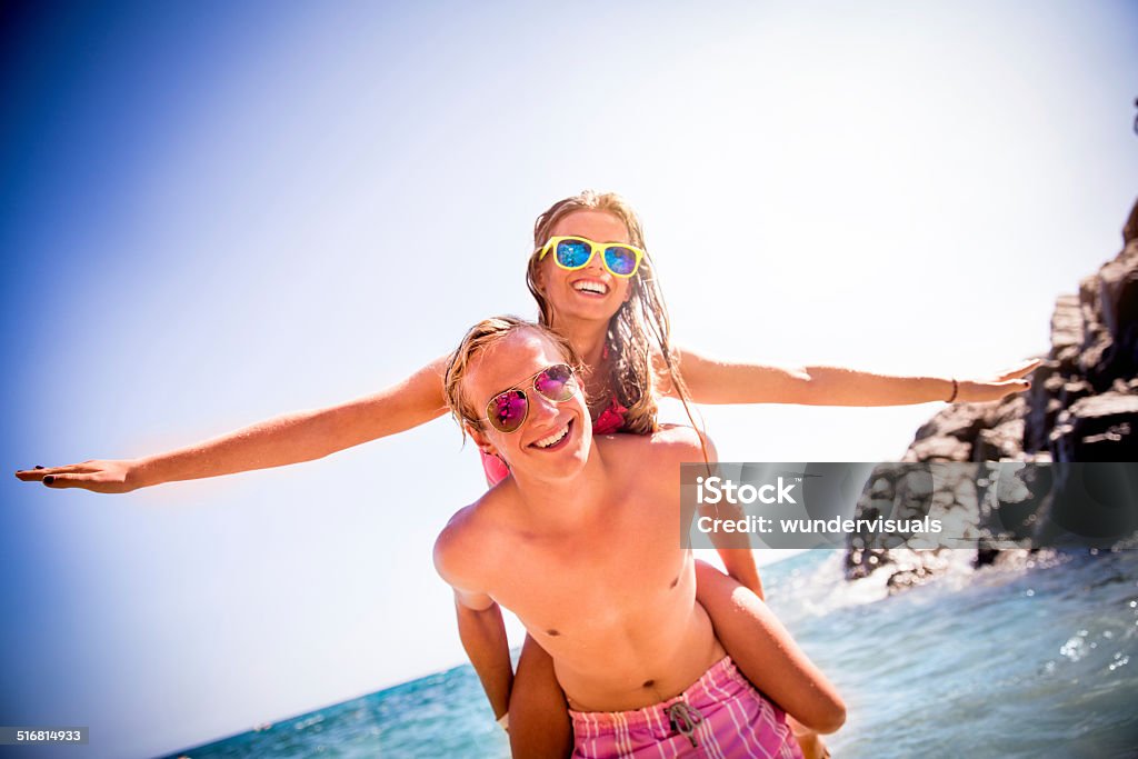 Couple Piggyback At Beach Guy piggybacks girl at beack Adolescence Stock Photo