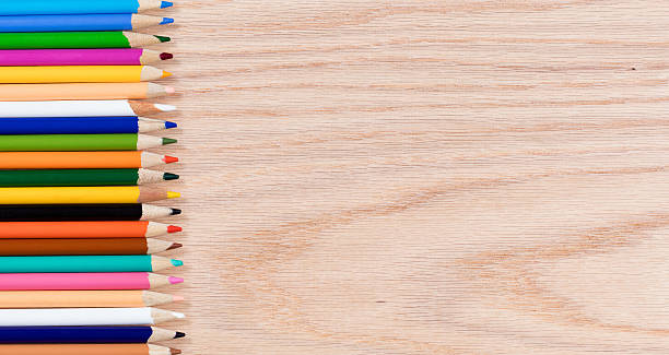 istock Colorful pencils lined up on oak wooden desktop 516815256