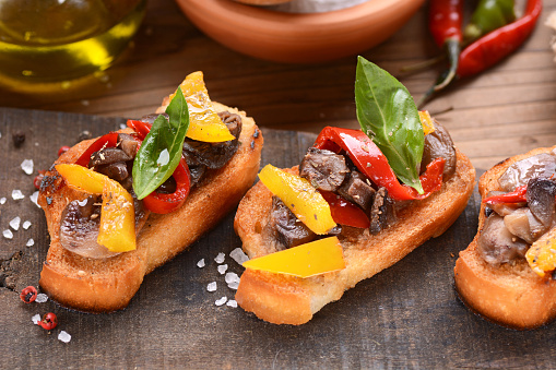 bruschetta with peppers and mushrooms on wooden board