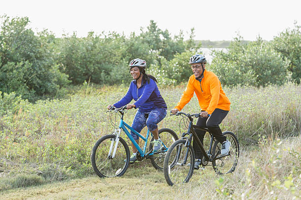 madura pareja afroamericana montar bicicletas en el parque - african descent cycling men bicycle fotografías e imágenes de stock