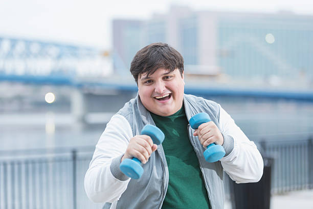 istock Young overweight man exercising with handweights 516815682