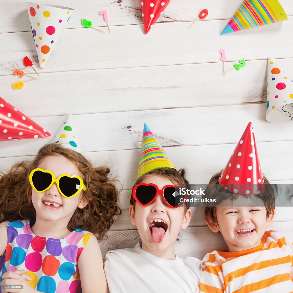 Happy child friend in carnival party. Happy child friend in carnival party, lying on a wooden floor. Happy childhood concept. High top view. Child Stock Photo