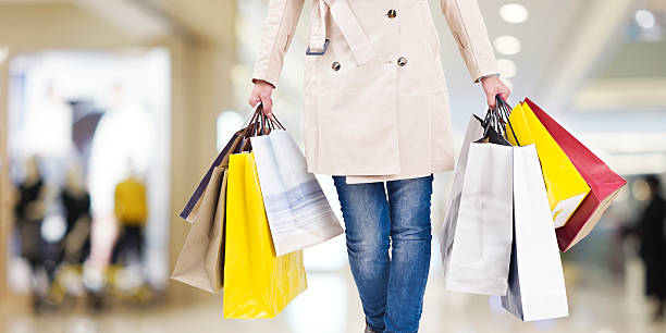 woman on a shopping spree woman with colorful shopping bags walking in modern mall. department store stock pictures, royalty-free photos & images