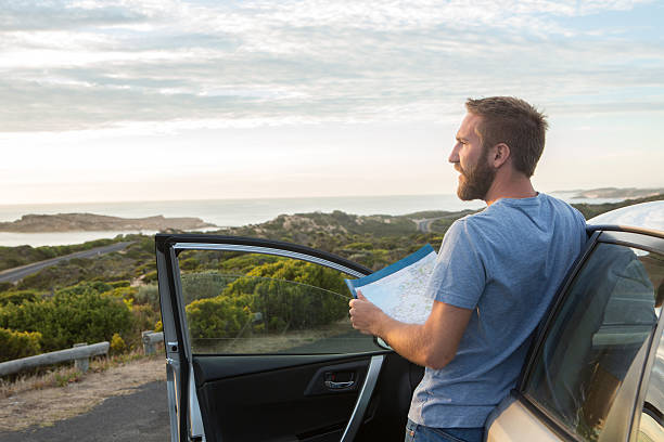 istock Young man on road reads map for directions 516824166