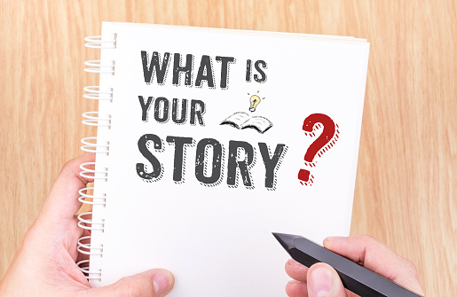 What is your story work on white ring binder notebook with hand holding pencil on wood table,Business concept.