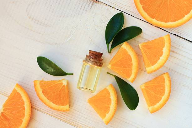 Orange aroma oil.  Bottle with essential oil, citrus scattered on wooden table. essential oil photos stock pictures, royalty-free photos & images