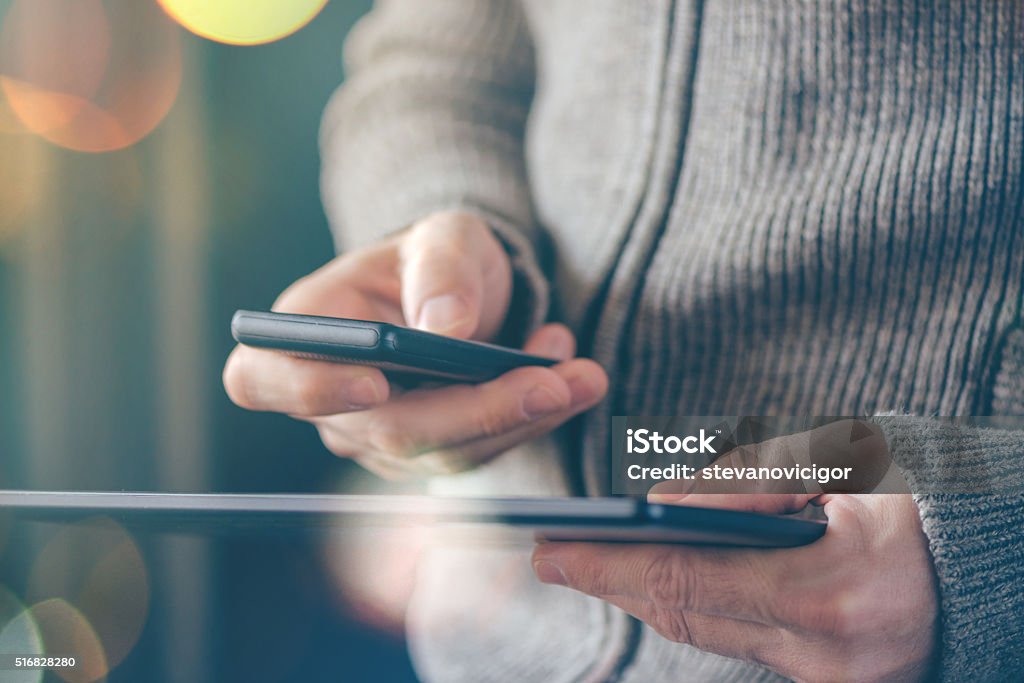 Smartphone and tablet data synchronization, man syncing files an Smartphone and tablet data synchronization, man syncing files and documents on personal wireless electronic devices at home, selective focus with shallow depth of field and bokeh light. Downloading Stock Photo