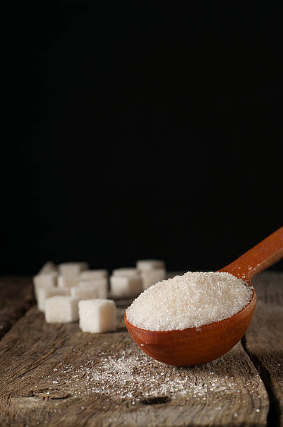 istock white sugar in a wooden spoon and sugar cubes 516844780
