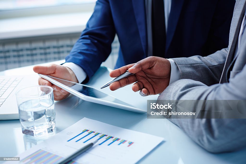 Pointing at touchpad Image of businessmen hands during discussion of data in touchpad at meeting Business Meeting Stock Photo