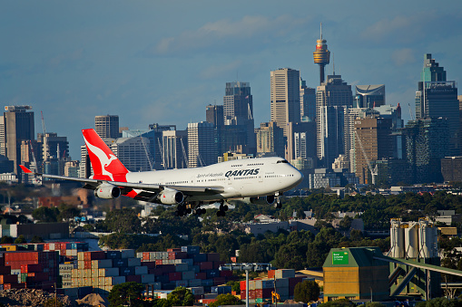 Sydney,Australia - March 19, 2016: A QANTAS Boeing 747 flies extremely low past buildings and industrial sites on its final approach to the city's airport.