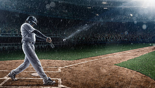 Baseball player in action A moment of baseball game  on a baseball stadium under dramatic stormy skies and rain. baseball player at bat stock pictures, royalty-free photos & images