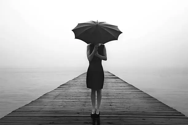 Photo of woman contemplates peacefully in front of a mysterious lake