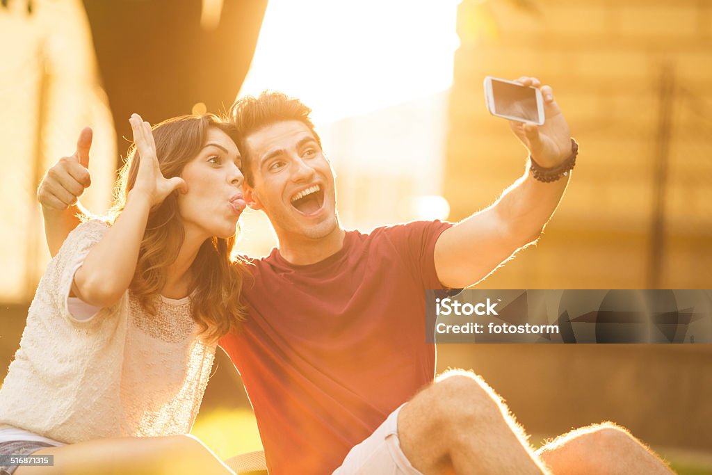 Couple taking silly self portraits on a mobile phone Young couple taking silly self portraits on a mobile phone. 20-29 Years Stock Photo