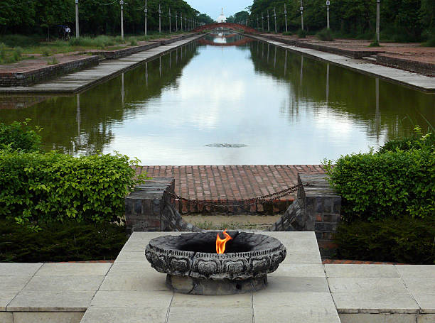 Sacred Flame at the Central Canal of Lumbini Sacred, never-dying flame in front of the central canal of Lumbini, birthplace of Buddha. The World Peace Pagoda is seen on the other end of the canal. lumbini nepal photos stock pictures, royalty-free photos & images