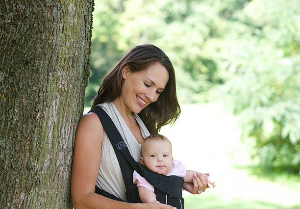 istock Smiling mother with cute baby in sling 516877377