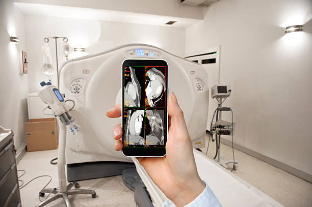 Smart Phone Application for Medical Scan Woman's hand holding smart phone, Medical Scan application on screen, modern hospital in the background.  Mobile Imaging Services stock pictures, royalty-free photos & images