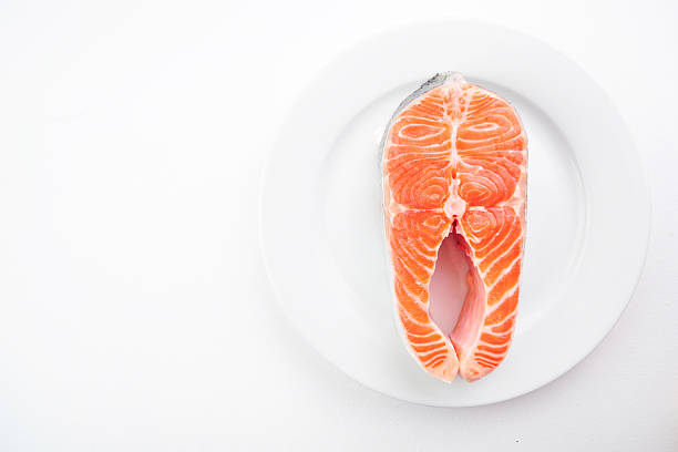Raw fillet of fresh salmon fish on white plate