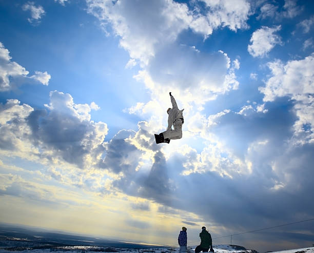 Silhouette the snowboarder jumping high in the blue sky and clouds