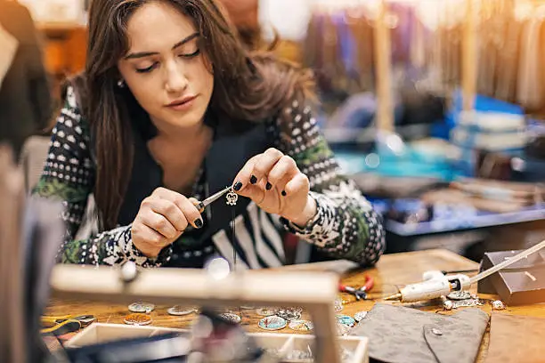 Young woman creating handmade jewelry in her studio