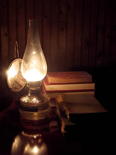 Oil lamp lit old books on the desk
