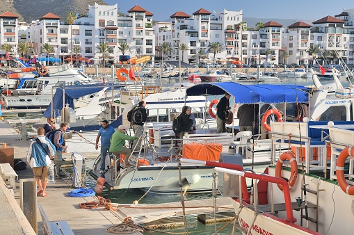 Agar, Morocco - February 17, 2016: A large group of birdwatchers board a tour boat in Agadir, Morocco in preparation for a pelagic birding excursion into the coastal Atlantic Ocean as part of their two week tour of the Atlas Mountains and southern Morocco. The Agadia Marina luxury condos line the harbor of this European vacation city