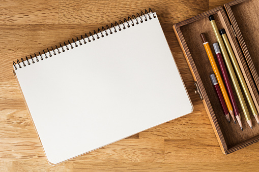 Blank notebook with pencils in box on the desk. Overhead view