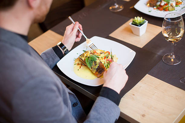 istock Man eating grilled salmon at restaurant 516899822
