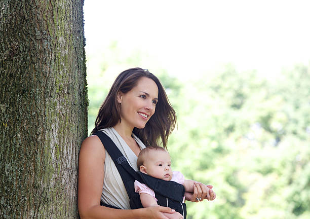 istock Mother smiling with infant in baby carrier 516909165