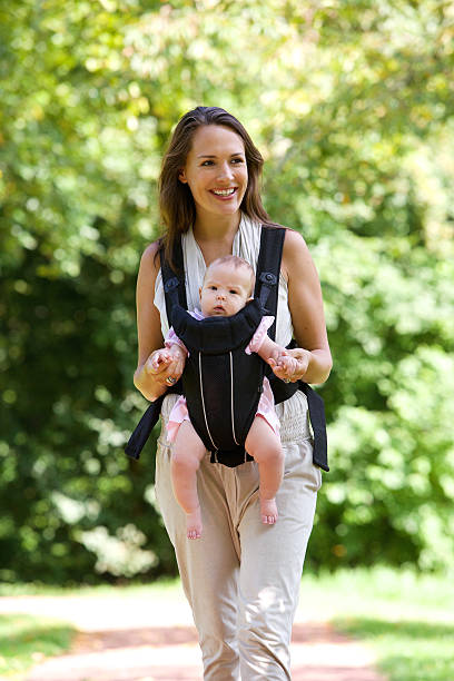 istock Smiling mother walking outdoors with baby in sling 516909791