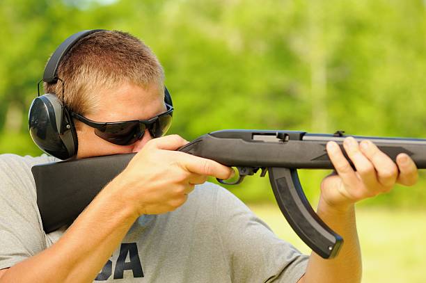 istock Young man firing semi automatic rifle 516912591
