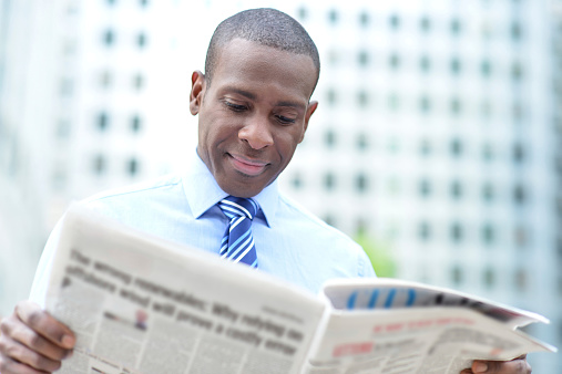 Handsome male business executive reading a newspaper