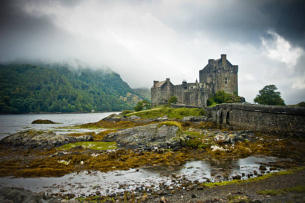 View of Eilean Donan Castle in Scotland Scotland, Uk - August 16, 2005: View of Eilean Donan Castle in cloudy day with dramatic light scottish highlands castle stock pictures, royalty-free photos & images