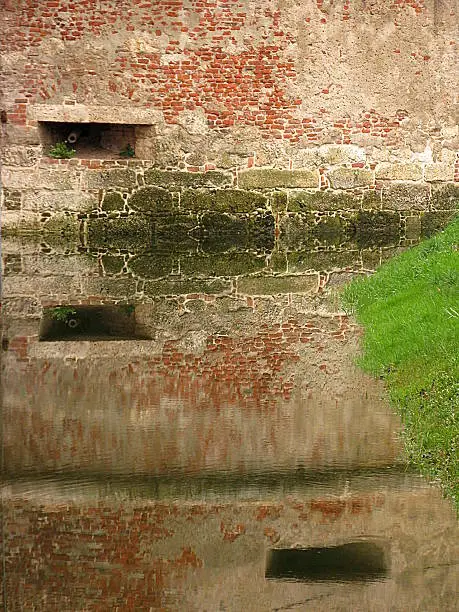 Medieval wall with Embrasure for Cannon surrounded by water. Detail of the military fort  called “The Old Town“ near the Croatian town of Sisak. It was built in 1541, and today there is a museum.