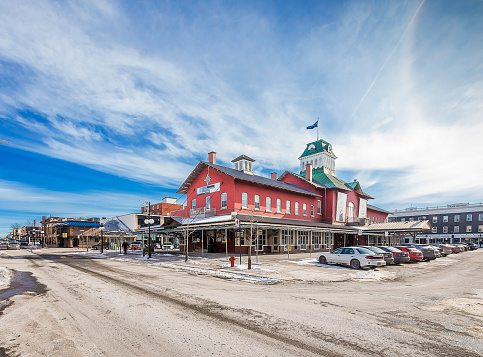 Saint-Hyacinthe, Canada- February 19 2016. The public market in the city of Saint-Hyacinthe on a sunny winter day. Motor vehicles parked around the building. Public Market St- Hyacinthe existed for almost 180 years. Built in 1830, it is the oldest public markets in Quebec. It has retained its original purpose while respecting the trends of today, which makes it a unique specialty market.