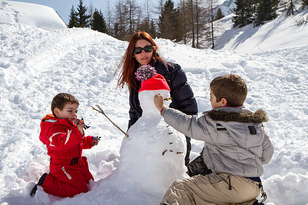 istock two brothers and mother with snowman 516923662
