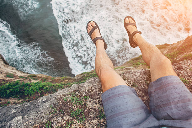 Brave man sitting on a high cliff above ocean