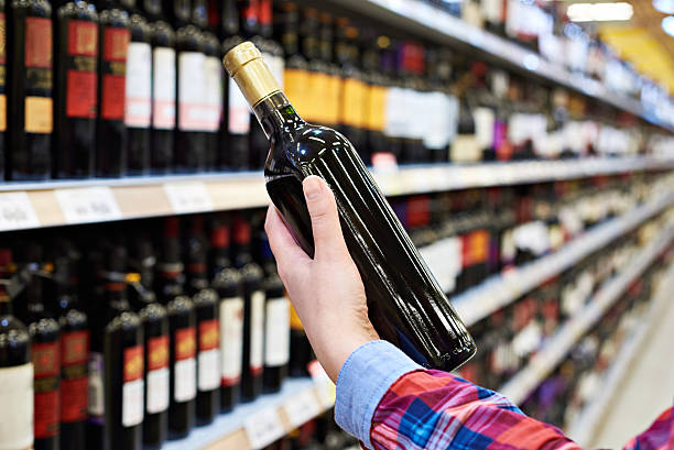 femme avec une bouteille de vin en magasin - liqueur photos et images de collection