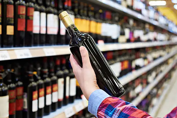 Woman with bottle of wine in the store