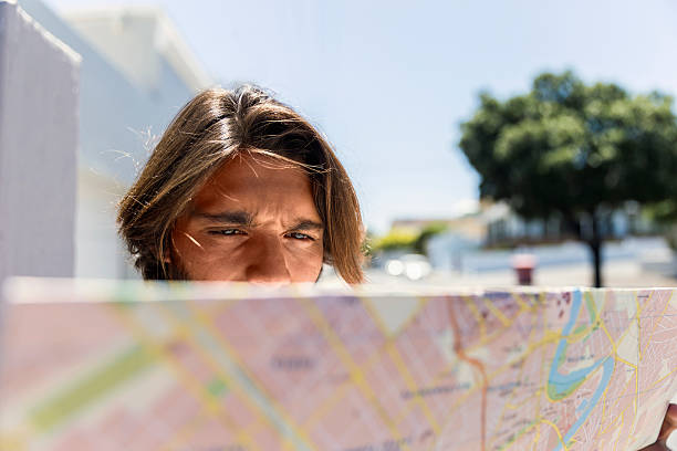 istock Serious man reading map in city on sunny day 516927184