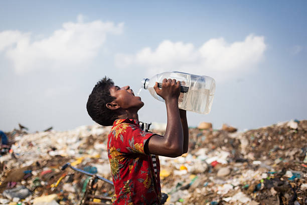 Precious Drinking Water Sylhet, Bangladesh-28 September 2014: A boy was drinking dirty water collected from a nearby source while he was working at a Wasteland for finding usable items sylhet stock pictures, royalty-free photos & images