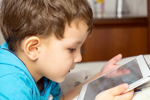 istock Boy with tablet lies in bed. 516931468