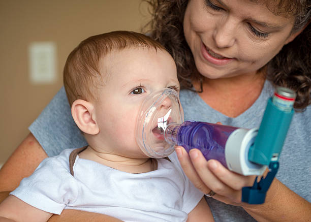 Infant getting breathing treatment from mother stock photo