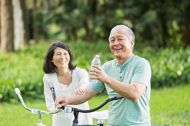 senior coppia biciclette equitazione - drinking men water bottle foto e immagini stock